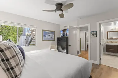 a bedroom with a white bed and a ceiling fan at Hideaway A Walk to the beach Downtown AC in San Clemente