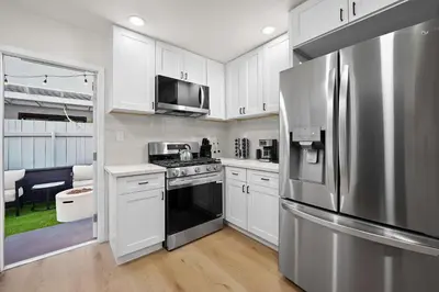 a kitchen with white cabinets and a stainless steel refrigerator at Explore North Park Chic 2br with Fire Pit Sleeps 6 in San Diego