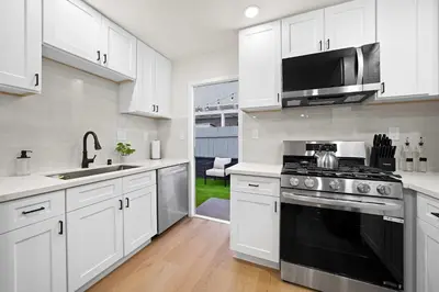 a kitchen with white cabinets and a black stove top oven at Explore North Park Chic 2br with Fire Pit Sleeps 6 in San Diego