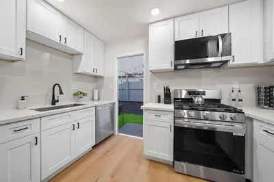 a kitchen with white cabinets and a stove top oven at Stylish 2BR SD Retreat Firepit plus Outdoor Lounge in San Diego