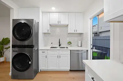 a kitchen with white cabinets and a washer and dryer at Stylish 2BR SD Retreat Firepit plus Outdoor Lounge in San Diego