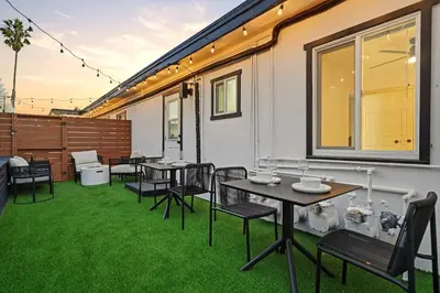 a group of tables and chairs on a patio with grass at Stylish 2BR SD Retreat Firepit plus Outdoor Lounge in San Diego