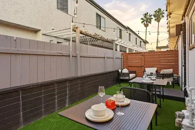an outdoor patio with tables and chairs and a fence at Stylish 2BR SD Retreat Firepit plus Outdoor Lounge in San Diego
