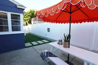 a patio with a table with a red umbrella at Sunset View home 2 min walk to beach parking in San Diego