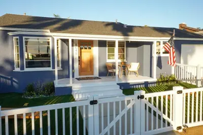 a house with a white fence and an american flag at Sunset View home 2 min walk to beach parking in San Diego
