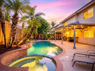 a swimming pool with palm trees and a house at Peaceful Poolside Perfection near Wine Country in Murrieta