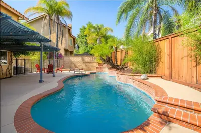a swimming pool with blue water in a backyard at Peaceful Poolside Perfection near Wine Country in Murrieta