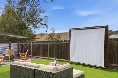 a large screen in a backyard with a lawn at New Modern 2BR Home with Movie theater, & Big Yard in La Mesa