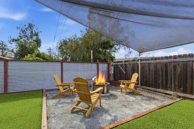 a backyard with a fire pit and chairs and a fence at New Modern 2BR Home with Movie theater, & Big Yard in La Mesa