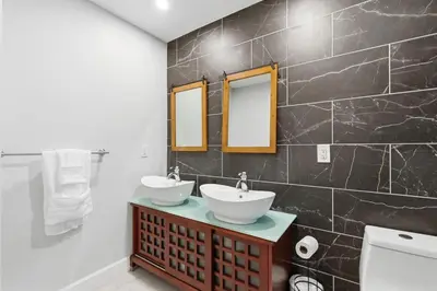 a bathroom with two sinks and a black tiled wall at New Modern 2BR Home with Movie theater, & Big Yard in La Mesa