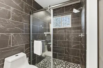 a bathroom with a toilet and a glass shower at New Modern 2BR Home with Movie theater, & Big Yard in La Mesa