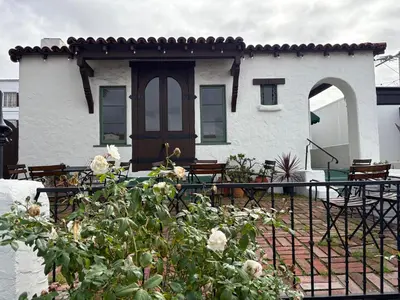 a white house with a gate and roses at Casa Cabrillo in San Clemente