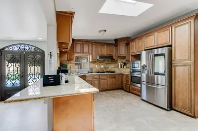 a kitchen with wooden cabinets and a stainless steel refrigerator at Spacious 4BR w/ Pool, Spa, Mini Golf & Game Lounge in Chula Vista