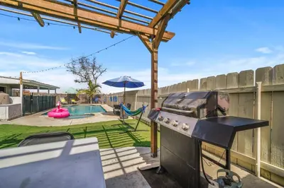 a barbecue grill in a backyard with a pool at Family Retreat w/ Theater, Pool & Outdoor Dining in Chula Vista