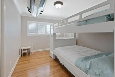 a white bedroom with a bunk bed and a wooden floor at SDSU Beach Cottage in San Diego