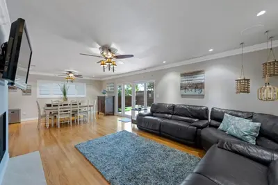 a living room with a black leather couch and a table at SDSU Beach Cottage in San Diego