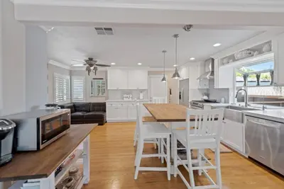 a kitchen with white cabinets and a table and chairs at SDSU Beach Cottage in San Diego