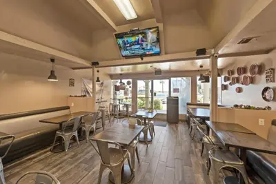 a restaurant with tables and chairs and a tv on the wall at SDSU Beach Cottage in San Diego