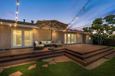 a backyard with a wooden deck and an umbrella at SDSU Beach Cottage in San Diego