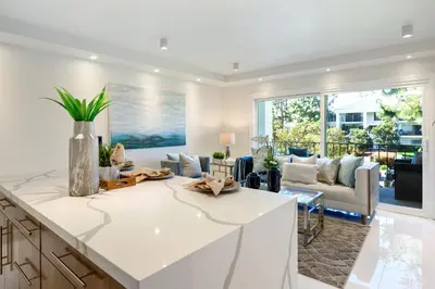 a kitchen with a white counter top and a living room at Newport Beach Lux in Newport Beach