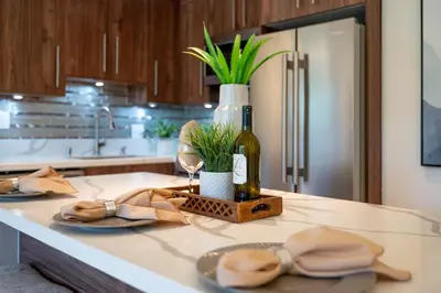 a kitchen counter with two plates and a bottle of wine at Newport Beach Lux in Newport Beach