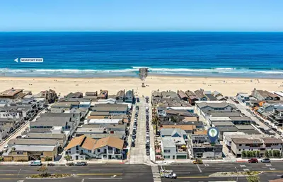 an aerial view of a beach with houses and the ocean at 8Br Retreat With Ac, Modern Upgrades, And Two Rooftop Decks By Beachview Rentals in Newport Beach