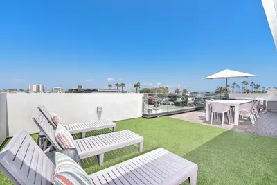 a patio with benches and tables on a roof at 8Br Retreat With Ac, Modern Upgrades, And Two Rooftop Decks By Beachview Rentals in Newport Beach