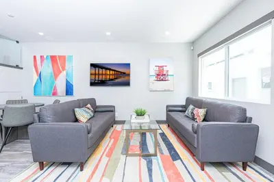 a living room with two couches and a table at 8Br Retreat With Ac, Modern Upgrades, And Two Rooftop Decks By Beachview Rentals in Newport Beach
