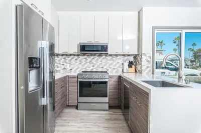 a kitchen with a refrigerator and a stove top oven at 8Br Retreat With Ac, Modern Upgrades, And Two Rooftop Decks By Beachview Rentals in Newport Beach