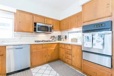 a kitchen with wooden cabinets and white appliances at Bayfront 4Br Retreat With Stunning Newport Harbor Views By Beachview Rentals in Newport Beach