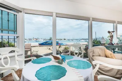 a room with a table and chairs and a view of the water at Bayfront 4Br Retreat With Stunning Newport Harbor Views By Beachview Rentals in Newport Beach