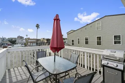 a table with a red umbrella on a balcony at 4Br Coastal Getaway Between The Bay And The Beach By Beachview Rentals in Newport Beach