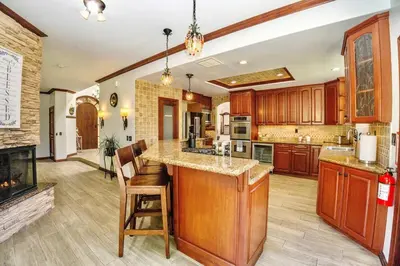 a large kitchen with wooden cabinets and a fireplace at Oceanside Tropical Resort with HEATED POOL & SPA! in Oceanside