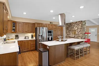 a kitchen with wooden cabinets and a stone wall at Serene 4BR La Mesa Hideaway in La Mesa