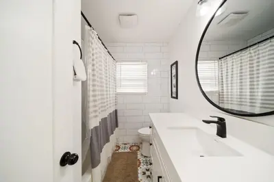 a white bathroom with a sink and a mirror at Little Italy Delight 3 bedroom backyard parking in San Diego