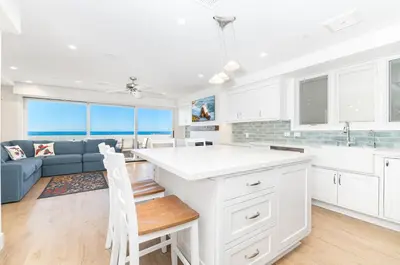 a kitchen with white cabinets and a blue couch at Remodeled Oceanfront Home On The Boardwalk By Beachview Rentals in Newport Beach