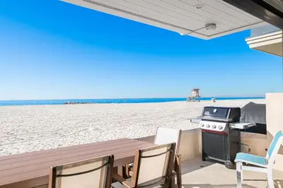 a table with chairs and a grill on the beach at Remodeled Oceanfront Home On The Boardwalk By Beachview Rentals in Newport Beach