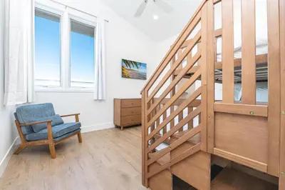 a stairway in a room with a blue chair and window at Remodeled Oceanfront Home On The Boardwalk By Beachview Rentals in Newport Beach