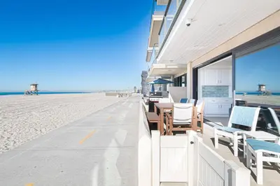 a building with chairs and tables on the beach at Remodeled Oceanfront Home On The Boardwalk By Beachview Rentals in Newport Beach