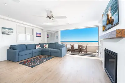 a living room with a blue couch and a fireplace at Remodeled Oceanfront Home On The Boardwalk By Beachview Rentals in Newport Beach