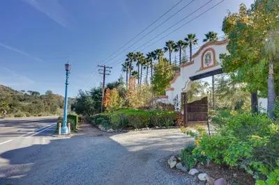 an empty street in front of a house with palm trees at Romantic Retreat at Rancho Las Lomas Pet Friendly