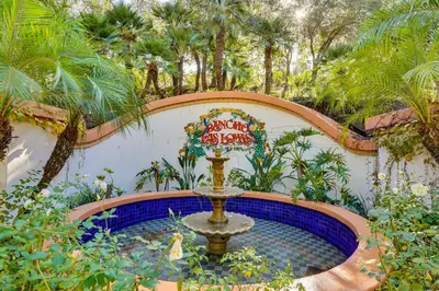 a fountain in the middle of a garden with palm trees at Spacious Courtyard and Spanish Charm Silverado Home