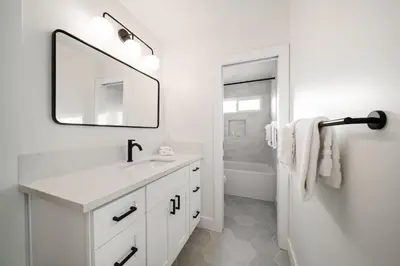 a white bathroom with a sink and a mirror at Cozy Coastal Townhome in the Heart of Pacific Beach in San Diego
