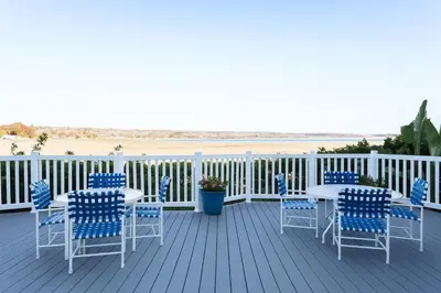 a deck with a table and chairs and the beach at Marbella Lane - Bayfront Bliss Sunset Views w Pool in San Diego