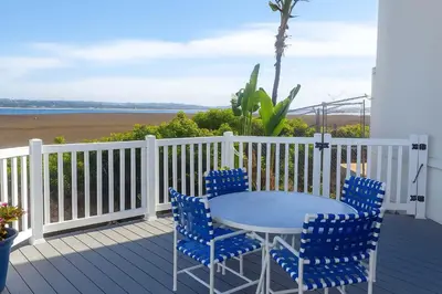 a table and chairs on a deck with the beach at Marbella Lane - Bayfront Bliss Sunset Views w Pool in San Diego