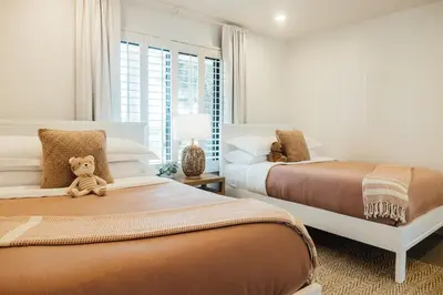 a bedroom with two beds with a teddy bear sitting on them at Palm Grove Luxe King, Wet Room & Chefs Kitchen in Carlsbad