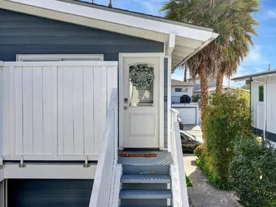 a blue house with a white door and stairs at Seaglass 222 in San Clemente