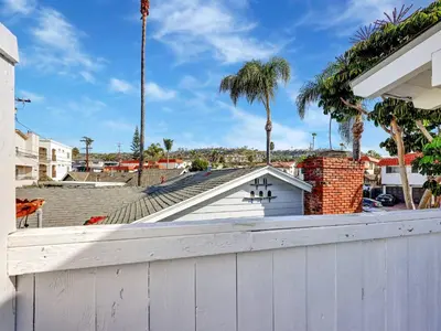a white house with palm trees in the background at Seaglass 222 in San Clemente