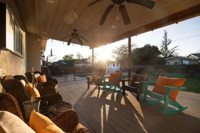 a covered deck with chairs and tables and the sun at Pool Oasis Central Villa in El Cajon