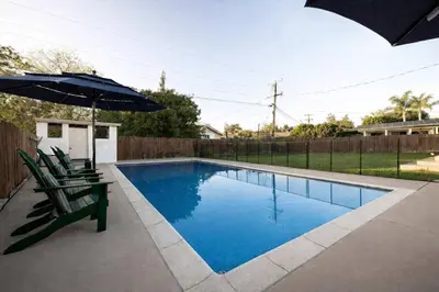 a swimming pool with two chairs and an umbrella at Pool Oasis Central Villa in El Cajon